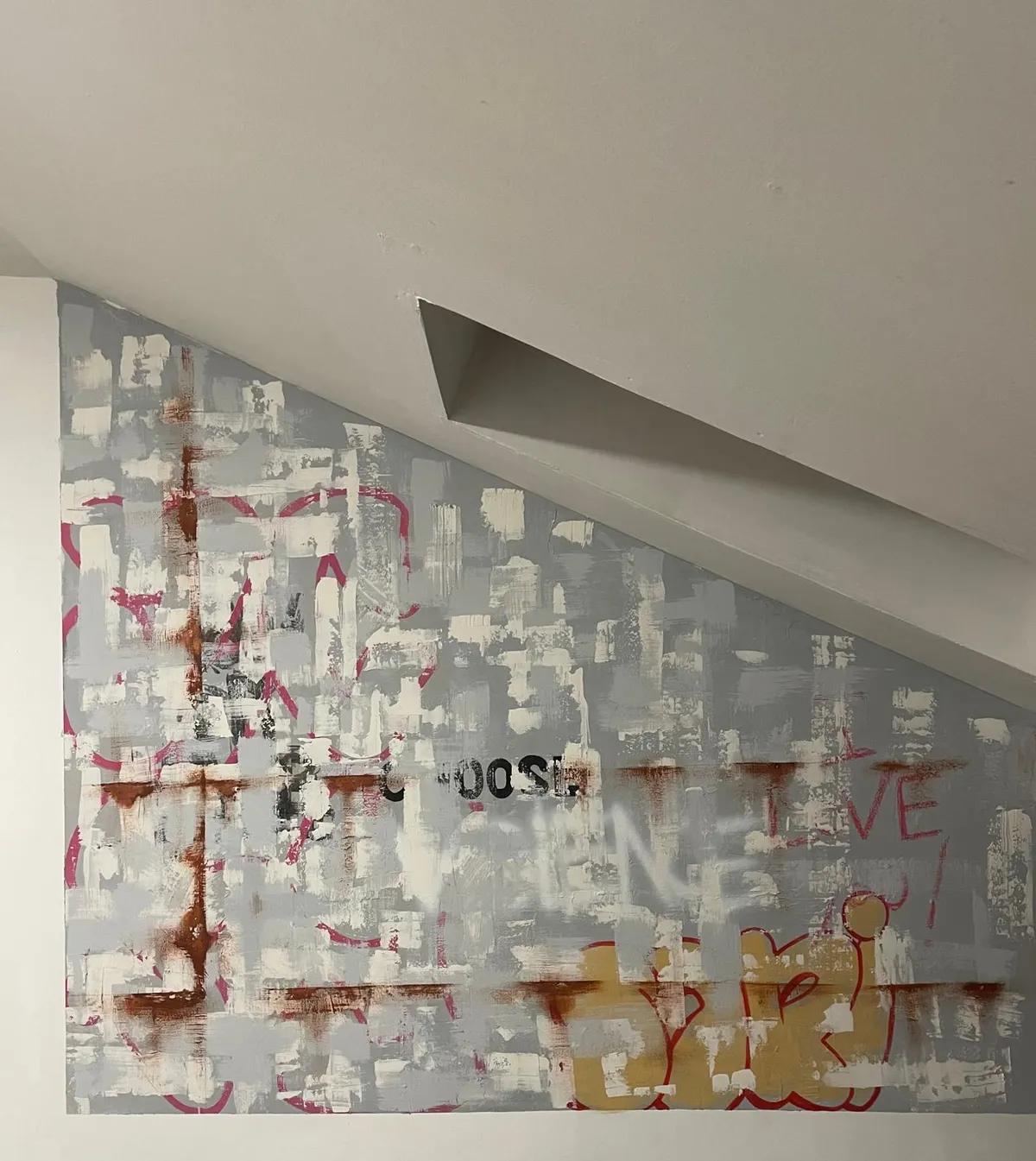 The same painted wall in the room, cut on a diagonal to fit beneath a sloping ceiling. The word CHOOSE and a yellow throw-up are visible in the lower half.